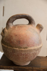 The antique North African vase's handmade form, showing the spout and handle in profile.