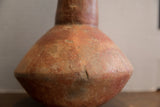 Close-up of the antique red slip ware vase showing its handmade, aged texture.