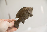 Vintage African fish sculpture held in hand to demonstrate its size and textured details.