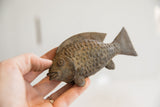 Vintage African fish sculpture held in hand, highlighting its rustic handmade texture and scale.