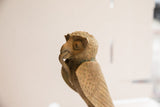Profile view of the vintage owl sculpture's head with a snake held in its curved beak.