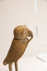 Side profile of the vintage owl's textured head holding a snake.