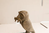 A detailed profile of the vintage African owl's carved face with a rat.