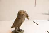 Profile view of the vintage African owl sculpture's textured head and beak.