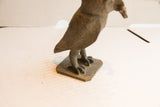 The textured square base and carved feet of the vintage African owl sculpture.