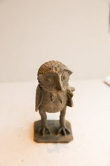 Front view of a handmade vintage African owl sculpture holding a rat.