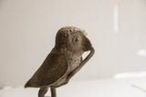 Profile view of the vintage owl sculpture's textured head and beak.