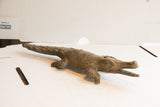 Side profile of a handmade African crocodile sculpture showing its carved scales and texture.