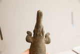 Textured body and long snout of a vintage crocodile sculpture from a low angle.
