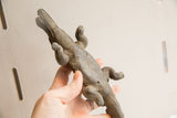 Angled view of the handmade crocodile sculpture showing its rustic, textured belly and legs.