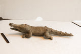 Side profile of a vintage crocodile sculpture showing its detailed, textured body and long snout.
