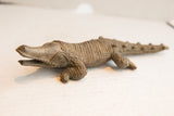 Angled profile of the vintage carved crocodile showing its open mouth and textured body.