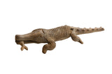 Vintage African crocodile sculpture with hand-carved scales holding a fish in its mouth.