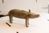 Side profile of the vintage African boar sculpture showing its textured body and curled tail.