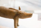 Profile view of a vintage African boar sculpture highlighting the carved eye and rustic texture.