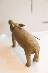 Rear angled view of the vintage African boar sculpture showing its textured body and tail.
