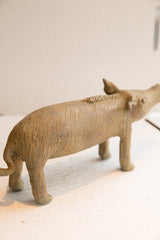 The vintage boar sculpture's elongated body, scored texture, and ridged spine.