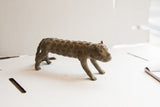 Side profile of a vintage African cheetah sculpture with textured, repeating spiral patterns.