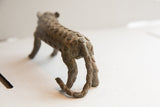 Rear view of vintage cheetah sculpture showing its textured, spiral-patterned body and curled tail.