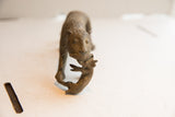 The aged, textured face of a handmade cheetah sculpture carrying its prey.