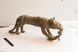Handmade African cheetah sculpture with spiral patterns shown in profile carrying prey.