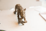 Carved spiral motifs on the face of a vintage African cheetah sculpture holding prey.
