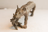 Aged patina and spiral details on the face of a vintage cheetah sculpture with prey.