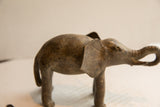 Side profile of a vintage elephant sculpture highlighting its textured ear and curled trunk.