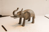 Handmade African elephant sculpture seen in profile, with a dark, aged patina.
