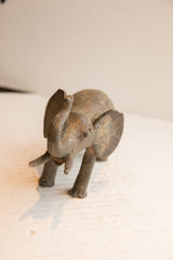 Vintage elephant sculpture seen from a high angle, highlighting its weathered texture and raised trunk.