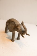 Vintage African elephant sculpture with a dark, textured patina and raised trunk.