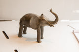 Side profile of a handmade elephant sculpture with a rustic, weathered texture.