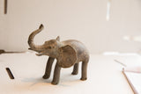 Vintage African elephant sculpture in profile with a rustic, handmade texture.