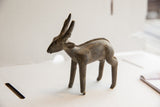 Side profile of a vintage handmade African antelope sculpture with a rustic texture.