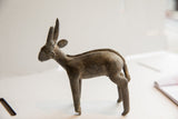 Side profile of the vintage African antelope sculpture showing its textured back and damaged leg.