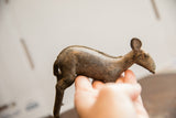 Profile view of the vintage African Ewe sculpture highlighting its rustic texture and form.