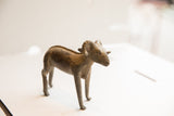 Angled view of a vintage African ram sculpture showing its handmade form and aged patina.