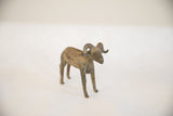 Profile view of a vintage African ram sculpture highlighting its textured patina and form.