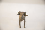 Eye-level frontal view of a vintage African ram sculpture's face and horns.