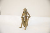 Side view of a vintage African monkey sculpture showing its seated pose and aged patina.