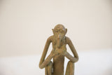 Expressive face of a vintage monkey sculpture with an aged, textured bronze-like patina.