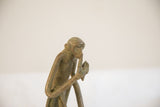 Close-up of the vintage monkey sculpture's pensive face and aged, patinated surface.
