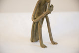 Side view of the vintage monkey sculpture showing its long legs and aged patina.