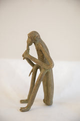 Profile view of a handmade African monkey sculpture showing its slender, seated form.
