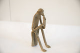 Full profile view of the vintage sitting monkey sculpture, highlighting its aged texture.