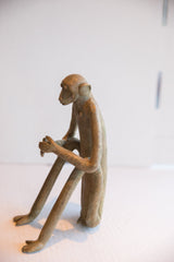 Side profile of a handmade African monkey sculpture showing its slender, seated form.