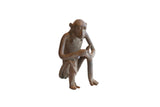 A handmade vintage African sculpture of a sitting monkey holding a banana.