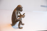 Profile view of the vintage sitting monkey sculpture showing its handmade texture.