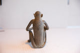 Rear view of the sitting monkey sculpture highlighting its weathered brown patina and form.