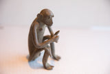 Angled view of the vintage monkey sculpture showing its textured handmade surface.